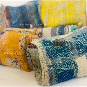 May include: Four colorful patchwork fabric pouches with a quilted design. The pouches are made of various fabrics in shades of blue, yellow, and brown. The pouches are arranged in a pile, with the largest pouch on the bottom and the smallest pouch on top. The pouches are handmade and have a unique, rustic look.