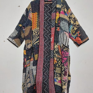 May include: A patchwork kimono-style robe with a variety of colorful fabric patterns. The robe features a mix of floral, geometric, and abstract designs in shades of black, red, yellow, and blue. It has long sleeves and a loose, flowing fit.