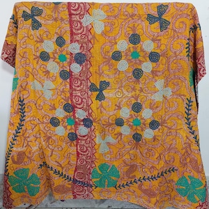 May include: A rectangular textile featuring a vibrant mustard yellow base with intricate red swirling patterns. The fabric is adorned with embroidered floral motifs in shades of teal, dark blue, and light gray, accented by visible running stitch details.