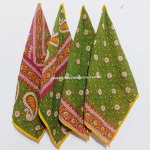 May include: Four kantha quilts in green and pink with floral and paisley patterns. The quilts have yellow borders and are folded in a triangle shape.