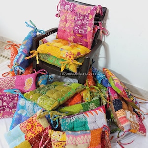 以下が含まれることがあります： 様々なパターンとテクスチャを持つカラフルなパッチワークの椅子クッションのコレクション。クッションはリサイクルされたサリーで作られており、どんな部屋にもボヘミアンスタイルのタッチを加えるのに最適です。