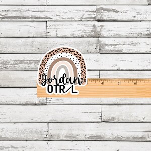 May include: A rainbow sticker with a leopard print design. The rainbow is in shades of brown, pink, and white. The text "Jordan OTR/L" is written below the rainbow.