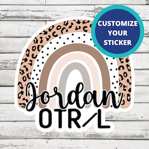 May include: A sticker with a rainbow design in shades of brown, pink, and gray. The rainbow is outlined in black and has a leopard print and polka dot pattern. The text "Jordan OTR/L" is written in black cursive font below the rainbow.