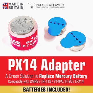 Op de afbeelding: Een rood-witte PX14-adapter voor camerabatterijen. De adapter is gelabeld met "PX-14 Adaptor" en "2.7 VOLT". Twee zilveren batterijen met blauwe plaklabels zijn inbegrepen.