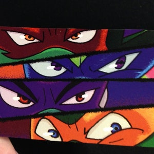 May include: A colorful illustration featuring the eyes of the Teenage Mutant Ninja Turtles. Each pair of eyes is set against a different background color, including red, purple, blue, and orange. The artwork is bold and graphic.