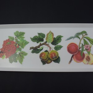 May include: A white rectangular serving tray with a decorative design of fruit. The tray features a redcurrant branch, a pear branch, and a peach branch with pink flowers.