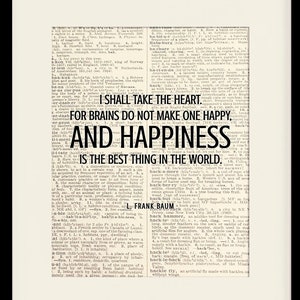 May include: A black framed print with a white background and black text. The text reads "I shall take the heart. For brains do not make one happy, and happiness is the best thing in the world."  The text is attributed to L. Frank Baum. The print is framed in a black frame with a white mat. The frame is 11 inches by 14 inches and the mat opening is 8 inches by 10 inches.