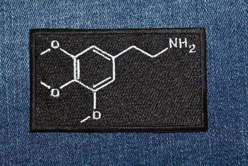 Peut inclure: Patch en tissu noir avec une structure chimique brod&eacute;e en blanc et le texte "NH2".