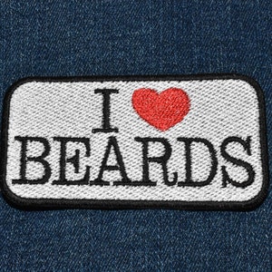 May include: White patch with black text that reads "I love beards" with a red heart in between the words. The patch is on a blue denim background.