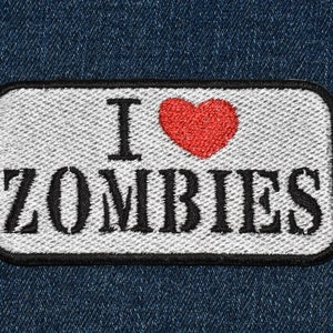 May include: White patch with black stitching and a red heart with the text "I love Zombies" on a blue denim background.