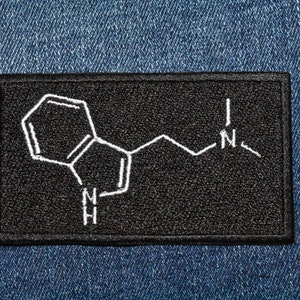 May include: Black patch with a white embroidered chemical structure of a molecule with the letters 'N' and 'H' on a denim background.