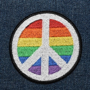 May include: A rainbow peace sign patch with a white background and black outline. The patch is made of embroidered fabric and is perfect for adding a touch of peace and love to your clothing or accessories.
