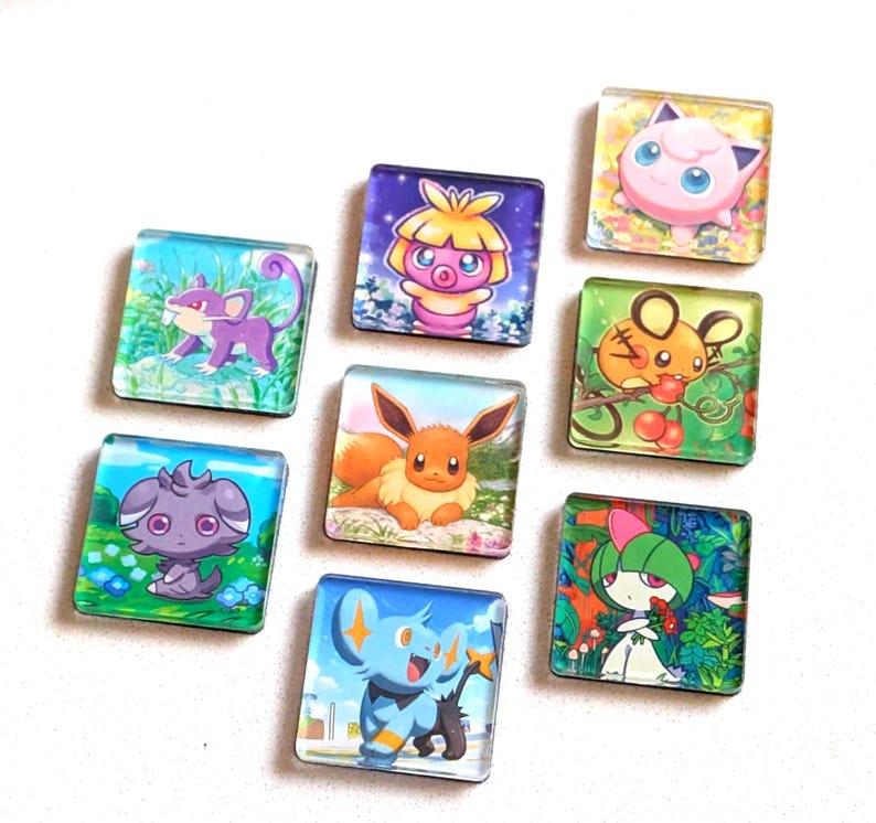May include: A collection of nine square glass magnets featuring colorful illustrations of various Pok&eacute;mon characters. Each magnet showcases a different character, including Eevee, Jigglypuff, and others, set against vibrant backgrounds. These magnets are ideal for decorating refrigerators or magnetic surfaces.