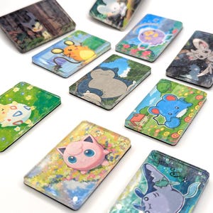 May include: A collection of rectangular, illustrated magnets featuring various cartoon characters. The magnets showcase vibrant colors and detailed artwork, with a white background. The characters are set against scenic backgrounds.