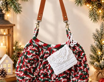 May include: A crochet handbag featuring a red, green, and white variegated yarn pattern with small white beads. The bag has a tan faux leather strap attached with bronze-toned metal clasps and includes a small, white, envelope-style crochet pouch.