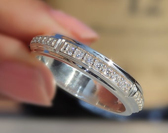 Puede incluir: Un anillo de banda de plata con una fila de pequeñas piedras transparentes engastadas en la banda.