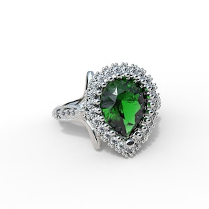 Peut inclure: Une bague en argent avec une pierre précieuse verte en forme de poire et un halo de petits diamants.