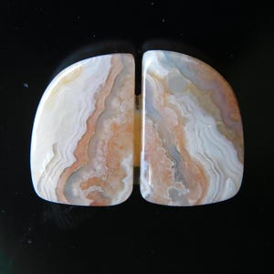 May include: Two halves of a polished agate stone with a white, pink, and brown banded pattern.