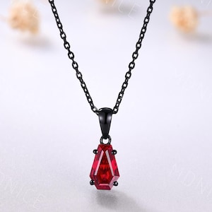 May include: A black chain necklace with a red gemstone pendant. The pendant is shaped like a teardrop and has a faceted design.
