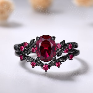 Könnte beinhalten: Ein schwarzer Ring mit einem großen ovalen Rubin-Edelstein, umgeben von kleineren Rubin-Steinen und schwarzen Blatt-Designs.