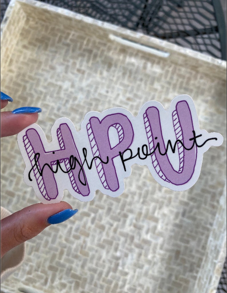 K&ouml;nnte beinhalten: Ein Aufkleber mit dem Text "HPU High Point" in einem lila-wei&szlig;en Design. Die Buchstaben "HPU" sind fett umrandet, w&auml;hrend "High Point" in Schreibschrift gehalten ist. Der Aufkleber befindet sich vor einem strukturierten Hintergrund.