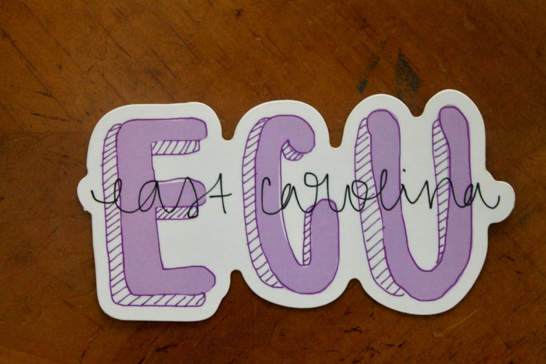 Puede incluir: Una pegatina blanca con el texto "ECU East Carolina" en letras moradas con burbujas. Las letras tienen un efecto 3D con l&iacute;neas diagonales para sombrear. Las palabras est&aacute;n escritas a mano.