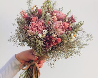 Könnte beinhalten: Ein Strauß aus Trockenblumen mit rosa Pfingstrosen, kleinen Kugelamaranthen und zartem Schleierkraut. Die Stiele sind zusammengebunden und mit einem hellbraunen Band fixiert, was ein strukturiertes Arrangement in gedeckten Tönen ergibt.