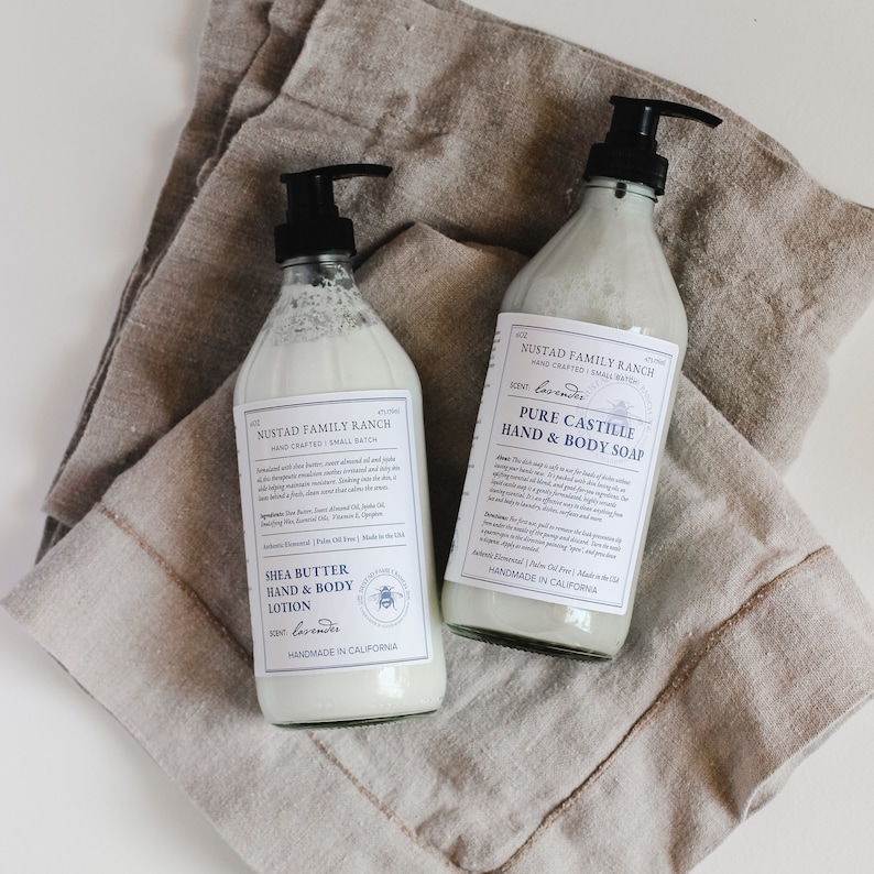 May include: Two clear glass bottles of hand and body care products. The bottles are labeled "NUSTAD FAMILY RANCH" and feature a lavender scent. One bottle is a shea butter hand and body lotion, the other is a pure castile hand and body soap. Both bottles are handmade in California.