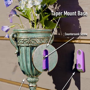 Peut inclure: Un vase en m&eacute;tal vert en forme d'urne avec des d&eacute;tails orn&eacute;s, mont&eacute; sur un mur avec une base en plastique violet et une vis frais&eacute;e. Le vase contient un bouquet d'hortensias bleus et blancs. Le texte "Taper Mount Base" et "Taper Wall Bracket" est visible sur l'image. Le texte "2 Vase Options: - M4 Nut - Use 16mm Screw - M4 Heatset Thread - Use 12mm Screw" est &eacute;galement visible sur l'image.