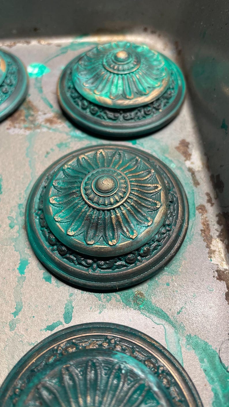 Peut inclure: Quatre ornements ronds d&eacute;coratifs de couleur vert sarcelle et or avec des motifs floraux complexes. Les ornements ont un centre sur&eacute;lev&eacute; avec un cercle plus petit au centre.