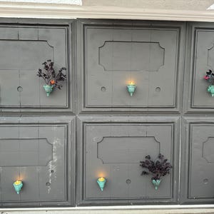 Peut inclure: Un mur gris avec six panneaux rectangulaires, chacun avec un cadre d&eacute;coratif. Chaque panneau a une petite plante en pot et un bougeoir allum&eacute;.