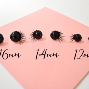 May include: Five black eye lash embellishments of different sizes on a pink surface. The embellishments are labeled 16mm, 14mm, and 12mm.
