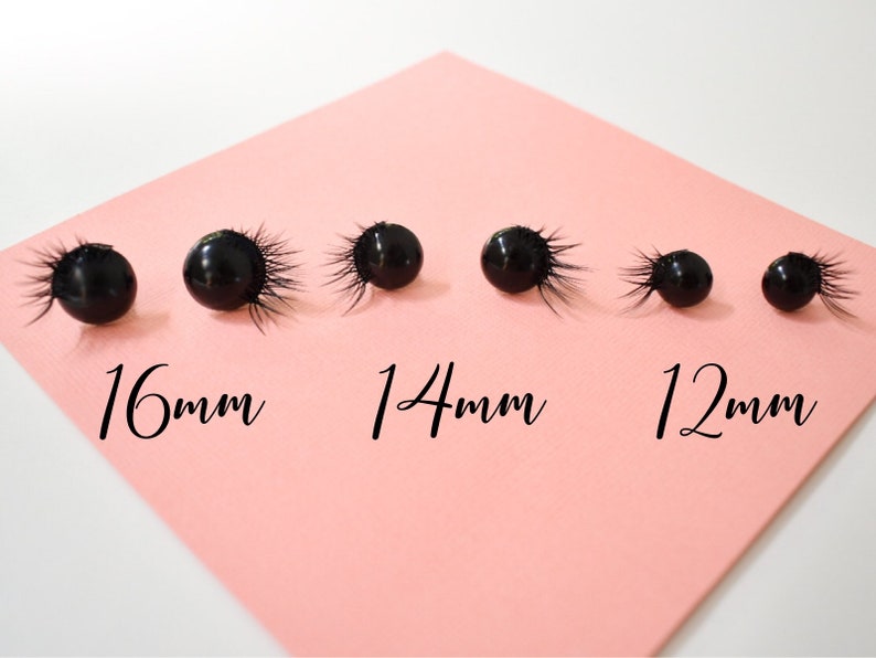May include: Five black eye lash embellishments of different sizes on a pink surface. The embellishments are labeled 16mm, 14mm, and 12mm.