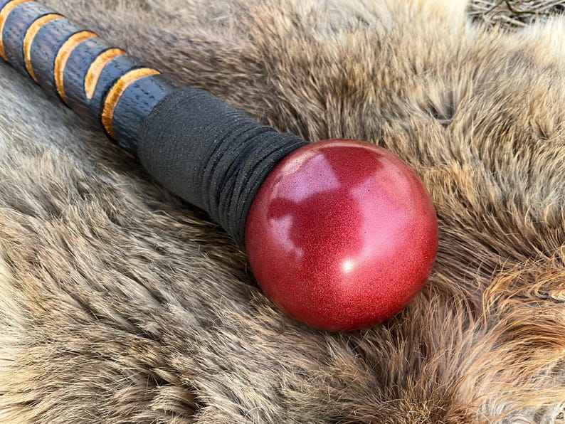 May include: A wooden walking stick with a black leather wrap and a red, round, metallic ball on the end.