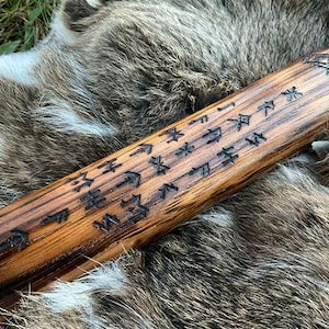 May include: A wooden staff with intricate carvings and runes. The staff is brown and has a natural wood finish. The runes are carved into the wood and are visible against the light brown background.