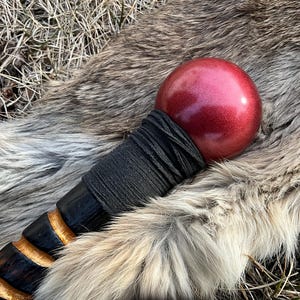May include: A wooden walking stick with a black leather wrap and a red, metallic sphere at the top.