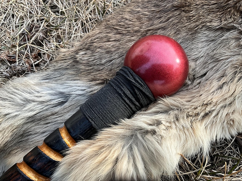 May include: A wooden walking stick with a black leather wrap and a red, metallic sphere at the top.