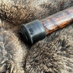 May include: A wooden walking stick with a black rubber tip. The stick has a dark brown finish and a natural wood grain.