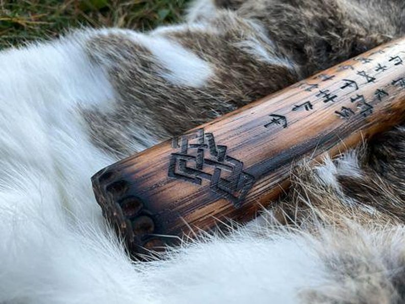 May include: A wooden staff with intricate carvings and runes. The staff is dark brown and has a smooth, polished finish. The runes are carved into the wood and are visible against the dark background.