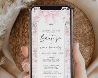 May include: A smartphone displays a baptism invitation with floral and bow accents. The invitation includes the text "Bautizo de Lucia Fernandez" and event details. The phone is held against a wooden background.