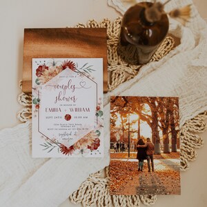 Puede incluir: Una invitación a una fiesta de pareja con detalles florales y los nombres Emilia y William. La invitación está sobre un bloque de madera, junto a una foto de una pareja en un parque. Un jarrón marrón con flores secas se encuentra sobre un mantel individual tejido.