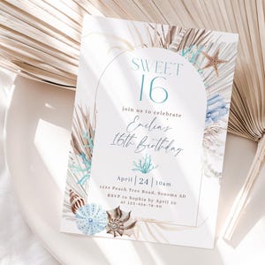 Può includere: Un invito bianco con un design ad acquerello blu e marrone che presenta conchiglie, foglie di palma e una stella marina. Il testo sulla carta recita "Sweet 16" e "Unisciti a noi per celebrare il 16° compleanno di Emelia". L'invito indica la data, l'ora, il luogo e le informazioni RSVP.