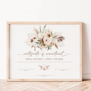 May include: A framed certificate of commitment featuring a floral design. The text reads "certificate of commitment" above the names "EMILIA WILLIAMS & JAMES WILLIAMS". The date of the commitment is April 24th, 2034.