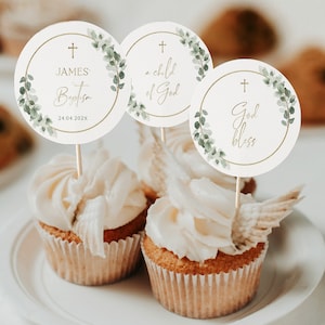 Könnte beinhalten: Drei weiße Cupcakes mit grünen und goldenen Cupcake-Toppern. Die Topper haben ein Kreuz, Grünzeug und Text, der "JAMES' Baptism 24.04.202X", "a child of God" und "God bless" lautet.
