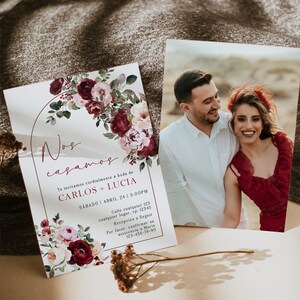 May include: A wedding invitation with a floral design in shades of pink and burgundy. The invitation features a gold arch with the text "Nos casamos" and the names "Carlos + Lucia". The invitation also includes the date and time of the wedding, as well as the address and RSVP information.
