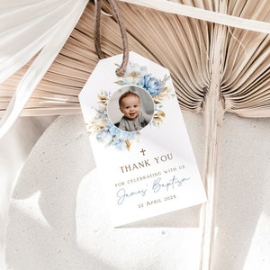 May include: A white thank you tag with a blue and gold floral design. A photo of a baby boy is in the center of the tag. The text reads "Thank You for celebrating with us James' Baptism 22 April 202X".
