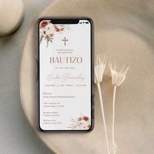 Könnte beinhalten: Ein Smartphone zeigt eine digitale Taufeinladung mit floralen Akzenten, einem Kreuzsymbol und dem Text ACOMPAÑANOSA SER PARTE DEL BAUTIZO DE NUESTRO HIJO Carlos Fernandez SÁBADO, 24 DE ABRIL, 10:00AM Padrinos: Elena Fuentes & Ricardo Salinas.