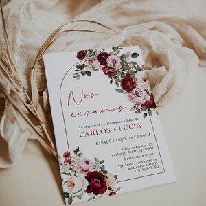 May include: A wedding invitation with a floral design in shades of pink and burgundy. The invitation reads "Nos casamos" and includes the names Carlos and Lucia, the date Saturday, April 24, and the time 3:00 PM. The invitation also includes the address and contact information for RSVP.