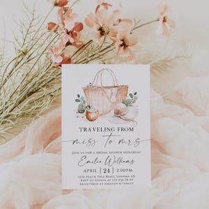 Könnte beinhalten: Eine Einladung zur Brautparty mit einer Aquarellillustration eines Picknickkorbs, Huts und Grünzeugs. Die Einladung lautet "Traveling from Miss to Mrs" und enthält Veranstaltungsdetails für Emilia Williams.