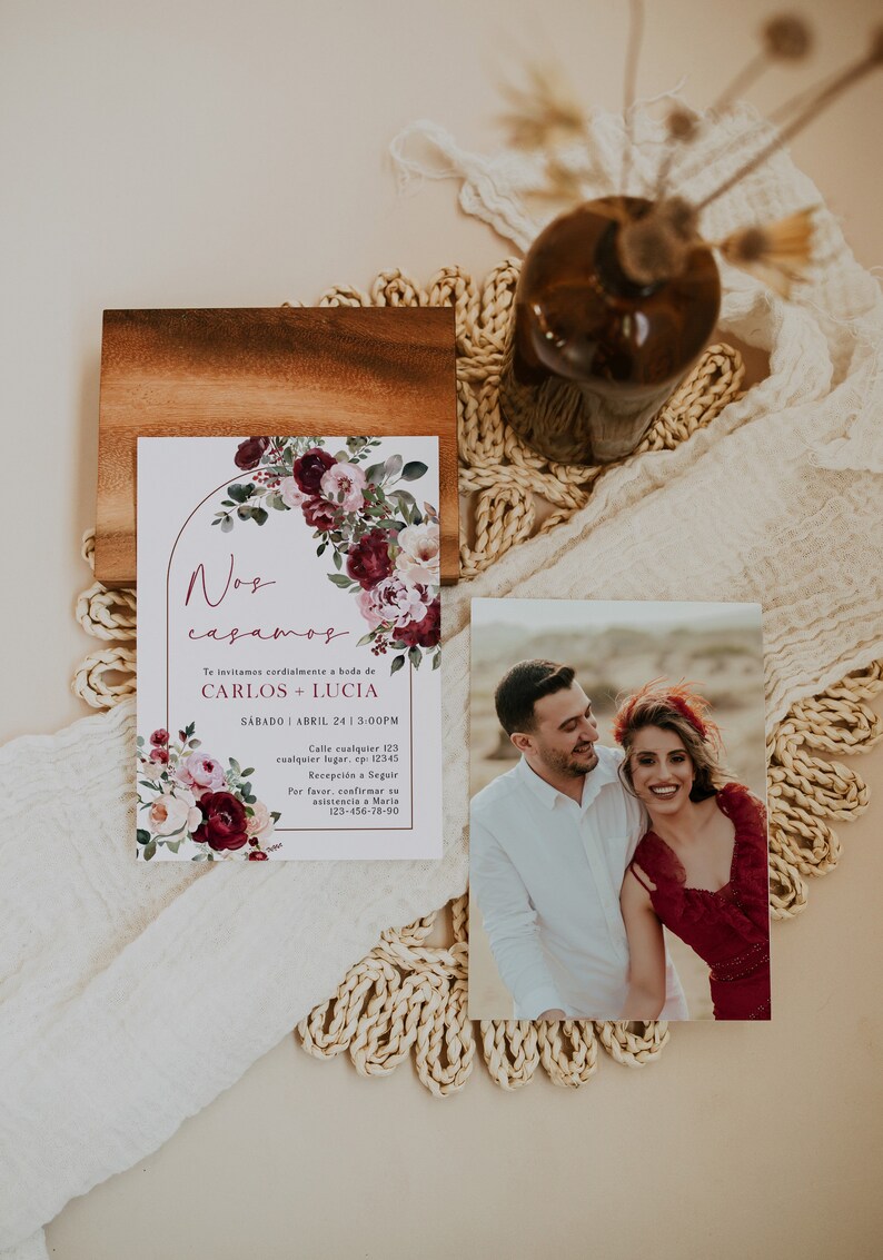 May include: Wedding invitation with a floral design in shades of burgundy and pink. The invitation features the text "Nos casamos" and the names "Carlos + Lucia". The invitation also includes the date and time of the wedding, as well as the address and contact information for RSVP.